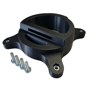 Puede incluir: Un soporte de montaje negro, circular e impreso en 3D, que presenta una abertura central, una ranura rectangular y tres brazos salientes con inserciones roscadas de metal. Cuatro pernos metálicos de color plateado se sitúan junto al soporte.