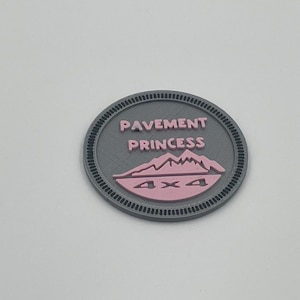 May include: A gray round badge with a pink mountain and the text "PAVEMENT PRINCESS" and "4x4" in the center.
