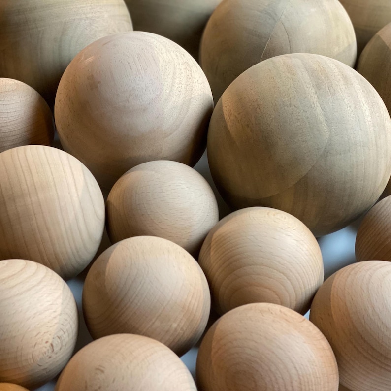 Puede incluir: Un grupo de esferas de madera de varios tama&ntilde;os, dispuestas en un patr&oacute;n aleatorio. Las esferas son de color marr&oacute;n claro y tienen un acabado liso y pulido.