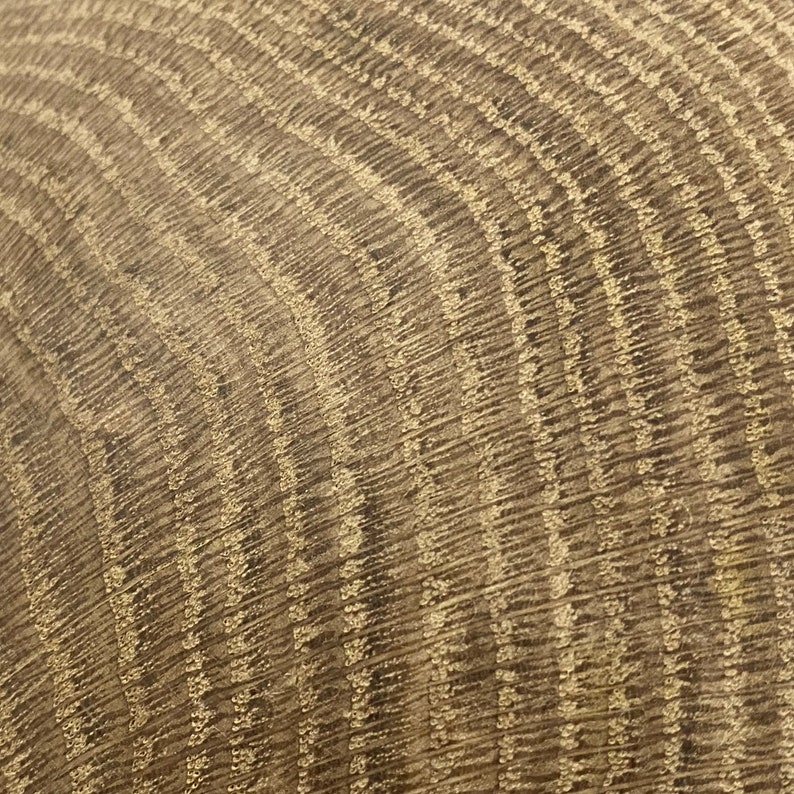 May include: Close-up of a textured, curved surface with a repeating pattern of vertical lines. The surface has a warm, neutral color palette with shades of brown and beige, creating a natural, organic aesthetic.