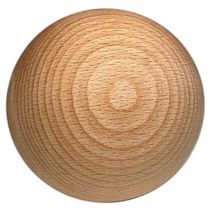 Peut inclure: Une boule sphérique en bois de couleur brun clair. La surface de la boule présente des motifs de grain circulaires concentriques, mettant en valeur la texture naturelle du bois. La boule est isolée sur fond blanc.