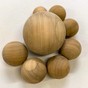 Puede incluir: Un grupo de ocho esferas de madera de diferentes tama&ntilde;os, todas con un acabado de madera natural. Las esferas est&aacute;n dispuestas en un racimo, con la esfera m&aacute;s grande en el centro.