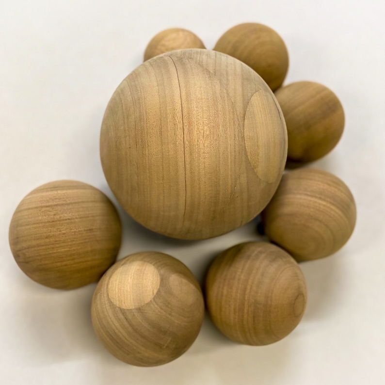 Puede incluir: Un grupo de ocho esferas de madera de diferentes tama&ntilde;os, todas con un acabado de madera natural. Las esferas est&aacute;n dispuestas en un racimo, con la esfera m&aacute;s grande en el centro.