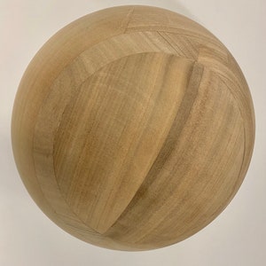 Puede incluir: Una esfera de madera marr&oacute;n claro con una superficie lisa y ligeramente texturizada. La esfera est&aacute; hecha de paneles de madera que se unen para crear un patr&oacute;n geom&eacute;trico.