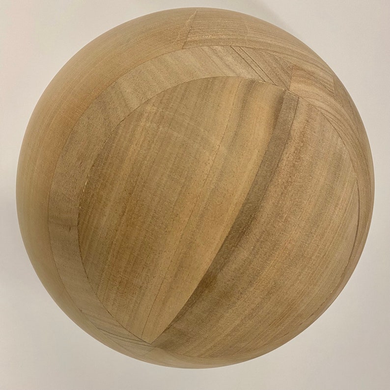 Puede incluir: Una esfera de madera marr&oacute;n claro con una superficie lisa y ligeramente texturizada. La esfera est&aacute; hecha de paneles de madera que se unen para crear un patr&oacute;n geom&eacute;trico.