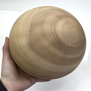 May include: A large, smooth, wooden sphere with a light brown color and a swirling grain pattern.