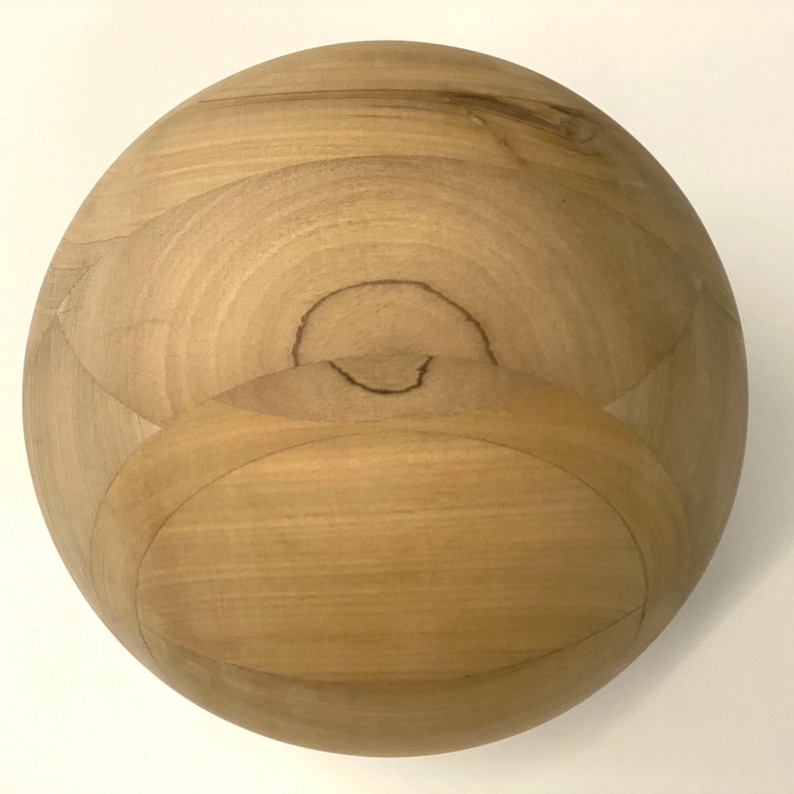 Puede incluir: Un cuenco de madera con un acabado liso de color marr&oacute;n claro. El cuenco es esf&eacute;rico y tiene una superficie ligeramente texturizada.