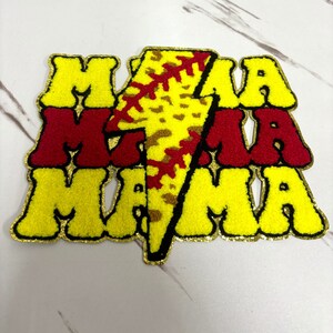 May include: Yellow, red and gold embroidered patch with the word "MAMA" repeated three times. A lightning bolt with a baseball design is in the centre of the patch.