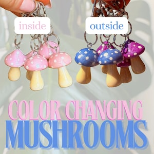 May include: Keyrings with colour-changing mushroom charms. The charms have pink, blue, and purple caps with white polka dots, and yellow stems. The text "inside" and "outside" are above the charms. The text "COLOR CHANGING MUSHROOMS" is below the charms.