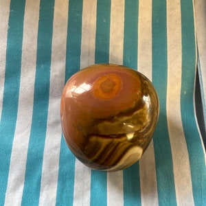 May include: A smooth, round, polished stone with brown, white, and pink swirling patterns.