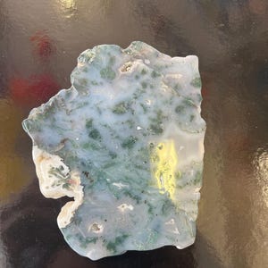 Puede incluir: Una rebanada de &aacute;gata verde y blanca con una forma natural irregular. La &aacute;gata tiene un patr&oacute;n de remolino de verde y blanco, con algunas &aacute;reas de amarillo.