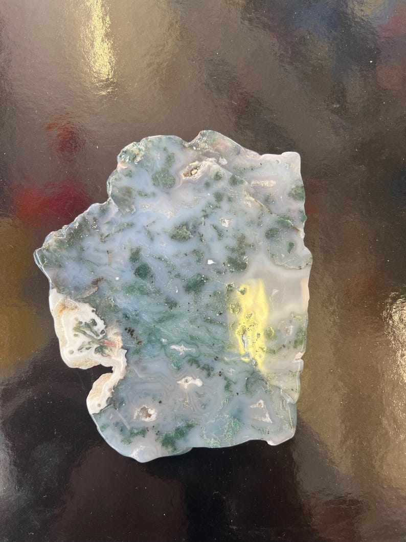 Puede incluir: Una rebanada de &aacute;gata verde y blanca con una forma natural irregular. La &aacute;gata tiene un patr&oacute;n de remolino de verde y blanco, con algunas &aacute;reas de amarillo.