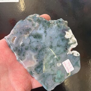 Puede incluir: Una losa de &aacute;gata verde y blanca con una forma natural irregular. La losa tiene una superficie lisa y pulida y presenta una variedad de patrones verdes y blancos. La losa est&aacute; etiquetada como "Moss Agate #32".