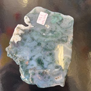 Puede incluir: Una losa de &aacute;gata verde y blanca con un borde &aacute;spero y natural. La losa tiene un patr&oacute;n de remolino de verde, blanco y gris. La etiqueta de precio dice "3,50 &euro;".