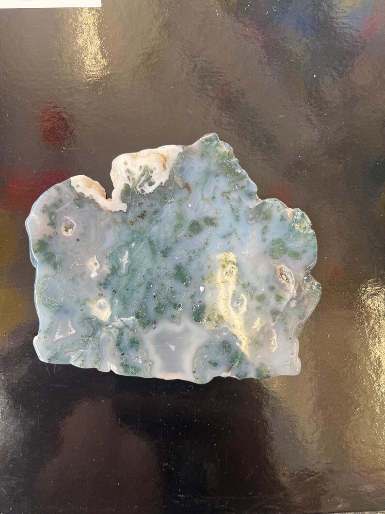 Puede incluir: Una rebanada de &aacute;gata verde y blanca con una forma natural irregular. La &aacute;gata tiene un patr&oacute;n de remolino de verde y blanco, con algunas &aacute;reas de blanco claro.