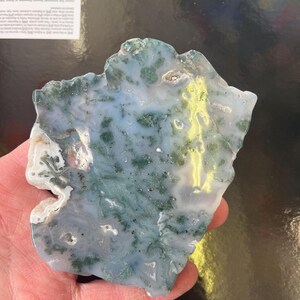 Puede incluir: Una rebanada de &aacute;gata verde y blanca con un patr&oacute;n &uacute;nico. La &aacute;gata tiene una superficie lisa y pulida y es una piedra natural.