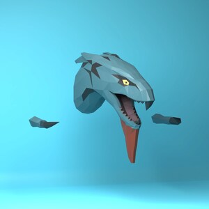 Könnte beinhalten: Ein blauer und schwarzer Origami-Schlangenkopf mit einer roten Zunge, die herausragt. Die Schlange hat ein gelbes Auge und ist vor einem hellblauen Hintergrund platziert.