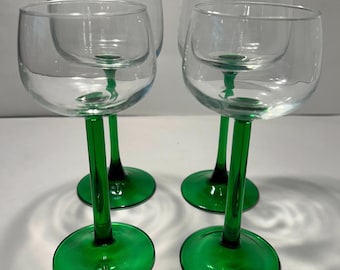 May include: Set of four clear glass wine glasses with green stems and bases.
