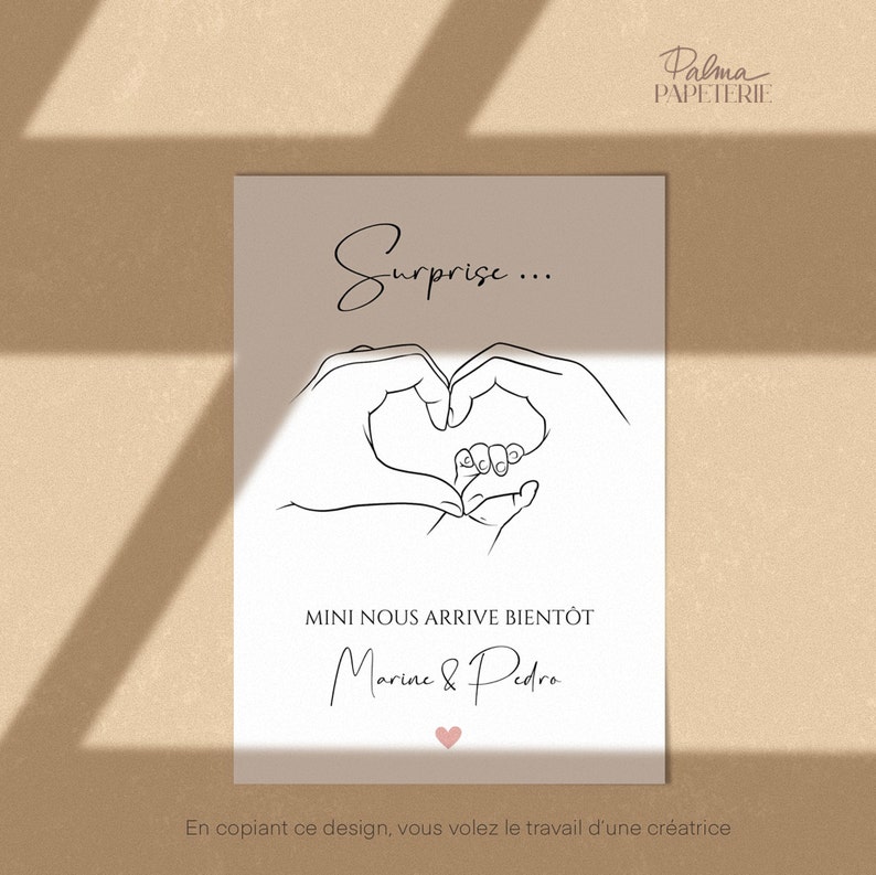 May include: A beige card with black line art of hands forming a heart around a baby's foot. The text "Surprise..." is above the heart. Below the heart is the text "MINI NOUS ARRIVE BIENT&Ocirc;T" and the names "Marine & Pedro". A pink heart is at the bottom.