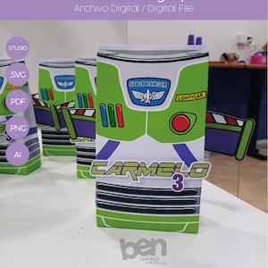Puede incluir: Una caja de favor de fiesta Buzz Lightyear verde, blanca y morada con el texto "SPACE RANGER" y "LIGHTYEAR" en ella. La caja está decorada con un botón rojo y un diseño a rayas morado y blanco. La caja está etiquetada "CARMELO 3".