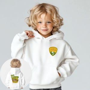 May include: A white hooded sweatshirt with a front pocket and a patch that says "Made in USA Joshua" with a mountain and tree graphic. The sweatshirt has a smaller image of the back of the sweatshirt, which says "Camp" and "Joshua Tree Campers".