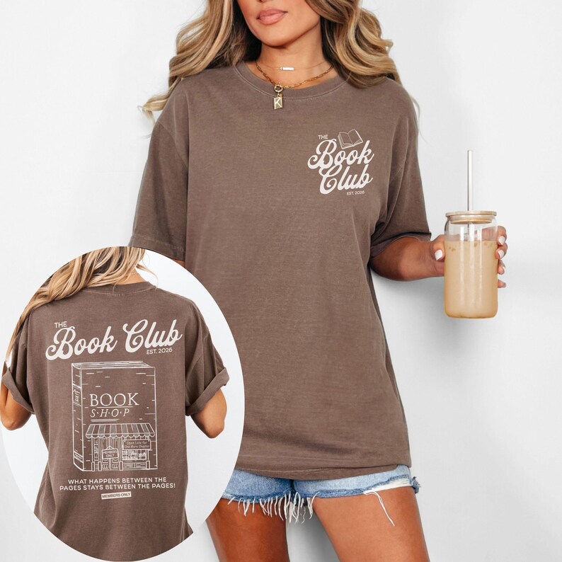 K&ouml;nnte beinhalten: Braunes T-Shirt mit dem Text "The Book Club" und einer Buchgrafik auf der Vorderseite. Auf der R&uuml;ckseite des Shirts befindet sich eine Buchladen-Grafik und der Text "What happens between the pages stays between the pages!"