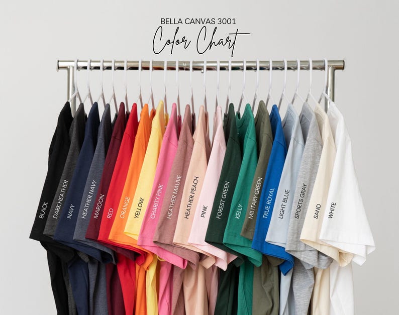 May include: A color chart of Bella Canvas 3001 t-shirts, displayed on a metal rack. The shirts are in various colors, including black, navy, red, yellow, pink, green, and blue. The text "Color Chart" is at the top.