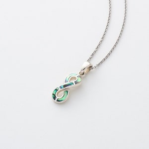 May include: A silver chain necklace with a green and white abalone shell infinity pendant.