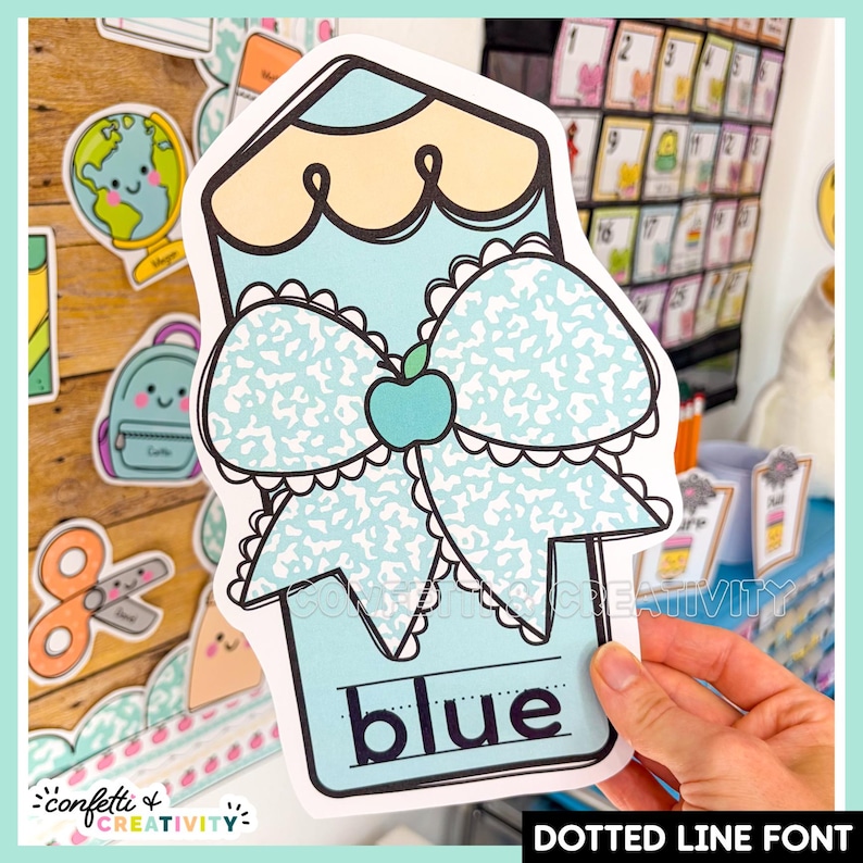 May include: A die-cut paper cutout shaped like a pencil in light blue and pale yellow. It features a large bow with a speckled pattern and a small teal apple icon in the center. The word blue is printed at the bottom in a dotted line font.