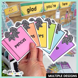 May include: A set of six colorful rectangular labels featuring a black and white patterned bow graphic at the top. Each label is a different color including pink, orange, yellow, green, light blue, and purple, with black text printed on each.