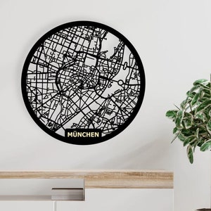 May include: Black and white circular wall art featuring a detailed map of Munich, Germany. The map is surrounded by a black circle and the word "MUNCHEN" is written in gold below the map.