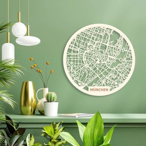 May include: A white circular wooden wall decor featuring a detailed map of Munich, Germany. The map is surrounded by a white border with the word "M&Uuml;NCHEN" in brown text at the bottom.