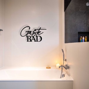 May include: A white bathtub with a chrome faucet and a sign that says "G&auml;ste BAD" in black lettering.