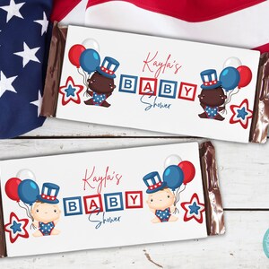 May include: Two white chocolate bar wrappers with red, white, and blue baby shower decorations. The wrappers feature a baby wearing a red, white, and blue hat and holding balloons. The text on the wrappers reads "Kayfla's Baby Shower".