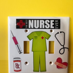 May include: White light switch cover decorated with medical-themed stickers. The stickers include a syringe, prescription bottle, scrubs, stethoscope, and a heart with a bandage. The text "THE BEST NURSE EVER" is displayed across the top.