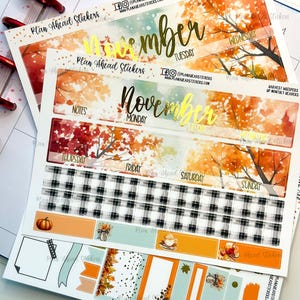 May include: A set of fall-themed planner stickers with a watercolor background featuring orange, yellow, and red leaves. The stickers include a calendar header with the month "November" in gold lettering, daily boxes, and a variety of decorative elements like pumpkins, plaid patterns, and fall leaves.