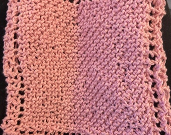 May include: A pink knitted dishcloth with a decorative border.