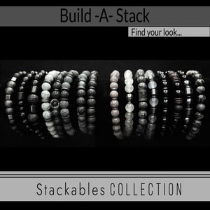 May include: A collection of stackable bracelets in various shades of gray, black, and white. The bracelets are made of different materials, including lava rock, agate, and hematite. The text "Build-A-Stack" and "Stackables COLLECTION" is visible in the image.