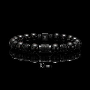 May include: A black beaded bracelet with a 10mm bead size. The bracelet features a mix of smooth and textured beads, with a central rectangular clasp. The bracelet is displayed against a black background.