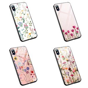 Op de afbeelding: Vier verschillende iPhone-hoesjes met bloemenontwerpen. De hoesjes zijn transparant en laten de kleur van de telefoon door het ontwerp heen schijnen. De ontwerpen omvatten een verscheidenheid aan bloemen, waaronder rozen, madeliefjes en wilde bloemen.