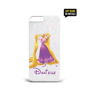 Op de afbeelding: Een witte iPhone-hoes met een glitterachtergrond met een cartoonafbeelding van Rapunzel uit Disney's Tangled. Rapunzel draagt een paarse jurk en houdt een borstel vast. De hoes heeft de naam "Danielle" in paars erop gedrukt.