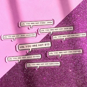 May include: Clear acrylic speech bubble-shaped pins with the text "LOL YOU ARE NOT PARK JIMIN", "LOL YOU ARE NOT KIM SEOKJIN", "LOL YOU ARE NOT JEON JUNGKOOK", "LOL YOU ARE NOT KIM TAEHYUNG", "LOL YOU ARE NOT BTS", "LOL YOU ARE NOT MIN YOONGI", "LOL YOU ARE NOT JUNG HOSEOK", and "LOL YOU ARE NOT KIM NAMJOON".