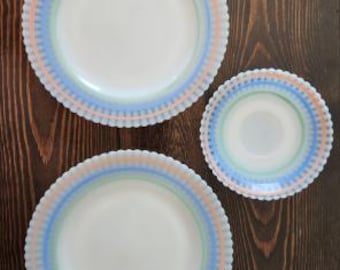 May include: Two large round plates and one smaller round bowl, all featuring a scalloped edge and a decorative border pattern of concentric rings in soft pastel shades of peach, light blue, and mint green on a white base.