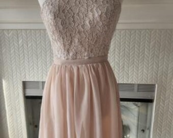 May include: A sleeveless dress featuring a light beige lace bodice with a high halter neckline and a solid light beige chiffon skirt that falls to the knees. The waist is defined by a simple band, and the skirt has a soft, gathered silhouette.