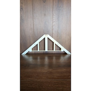 Puede incluir: Una armadura de techo triangular de madera blanca con cinco vigas y una viga de soporte central. La armadura está unida a una superficie de madera con tornillos.