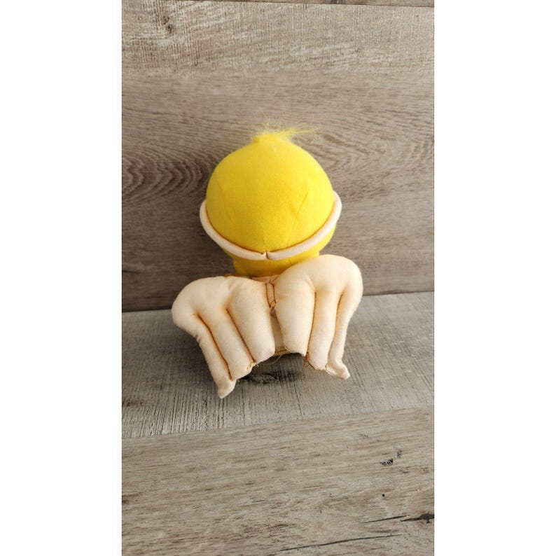 May include: A yellow plush toy with white wings. The toy is shaped like a bird and has a fluffy texture.