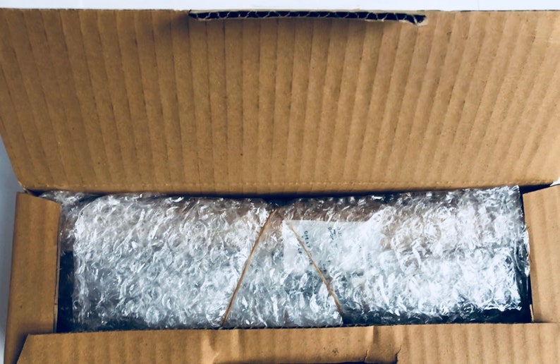 May include: An open cardboard box with bubble wrap inside. The bubble wrap is secured with a rubber band.