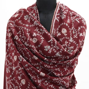 May include: A maroon shawl with a white floral pattern. The shawl is made of a soft, luxurious fabric and has a delicate fringe.