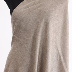 May include: A light brown shawl made of a soft, woven fabric. The shawl has a subtle shimmer and a slightly textured surface.