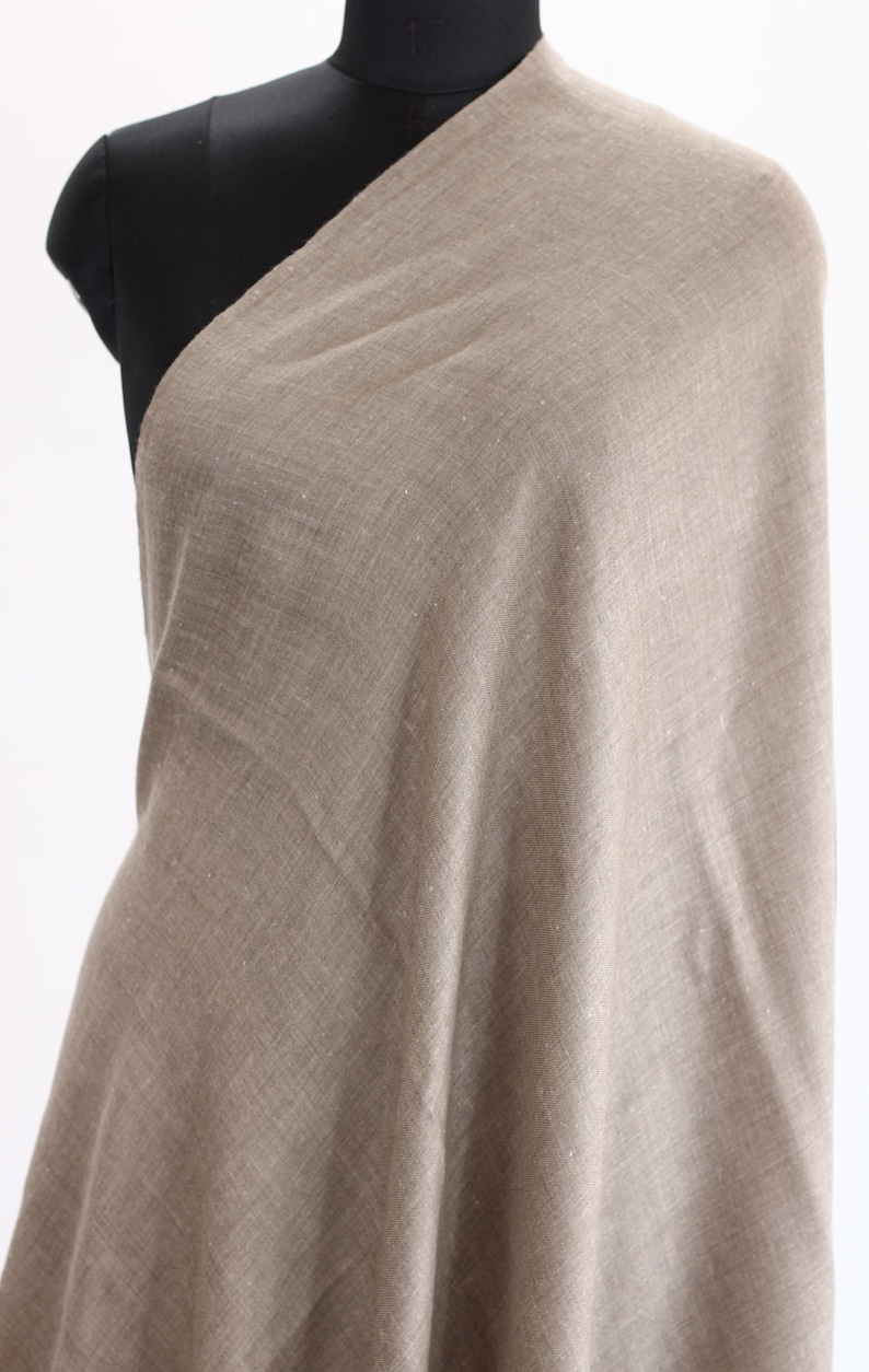 May include: A light brown shawl made of a soft, woven fabric. The shawl has a subtle shimmer and a slightly textured surface.